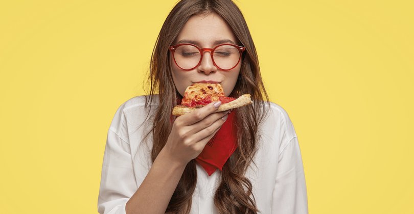 Mulher jovem comendo sua pizza deliciosa, com até os olhinhos fechados